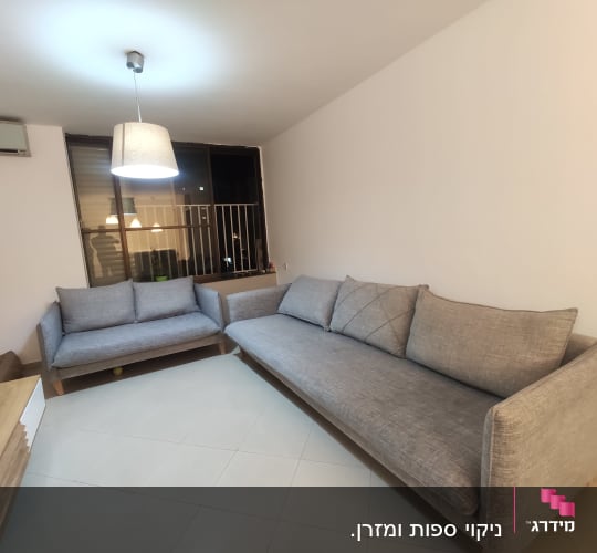 שתי ספות אפורות בחדר מואר עם מנורה תלויה